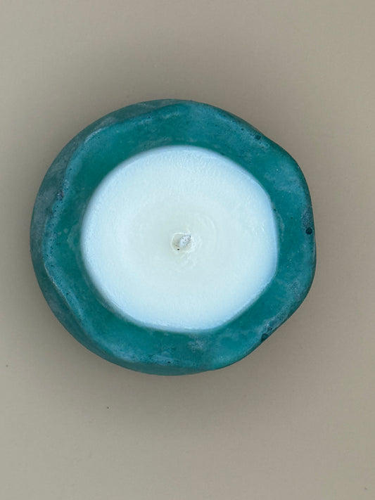 Top view Teal Concrete container with a white candle inside on a beige background