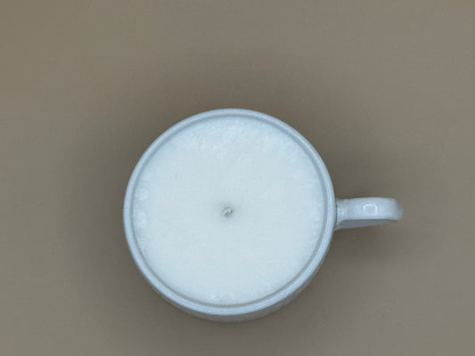 Top view White ceramic mug with woven pattern containing a candle on a beige background