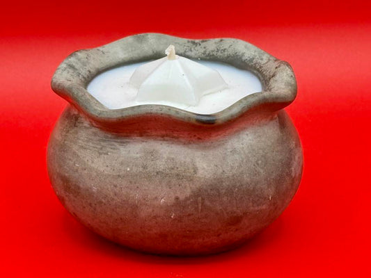 Concrete pot with a white candle inside on a red background
