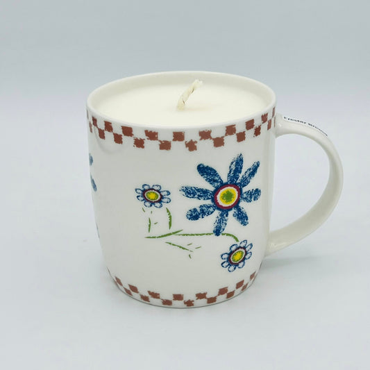 Ceramic mug with floral designs and a candle inside on a white background