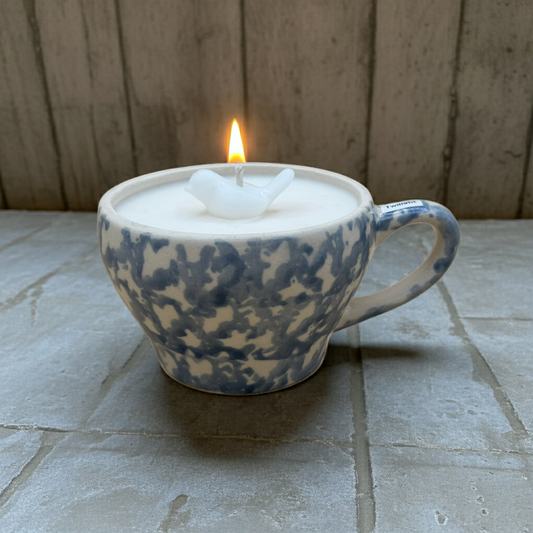 Candle in a ceramic mug with a wooden background