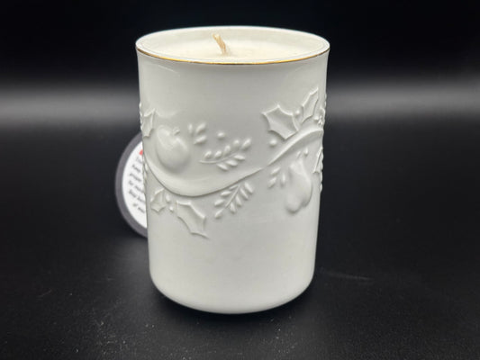 White ceramic candle holder with embossed design on a black background