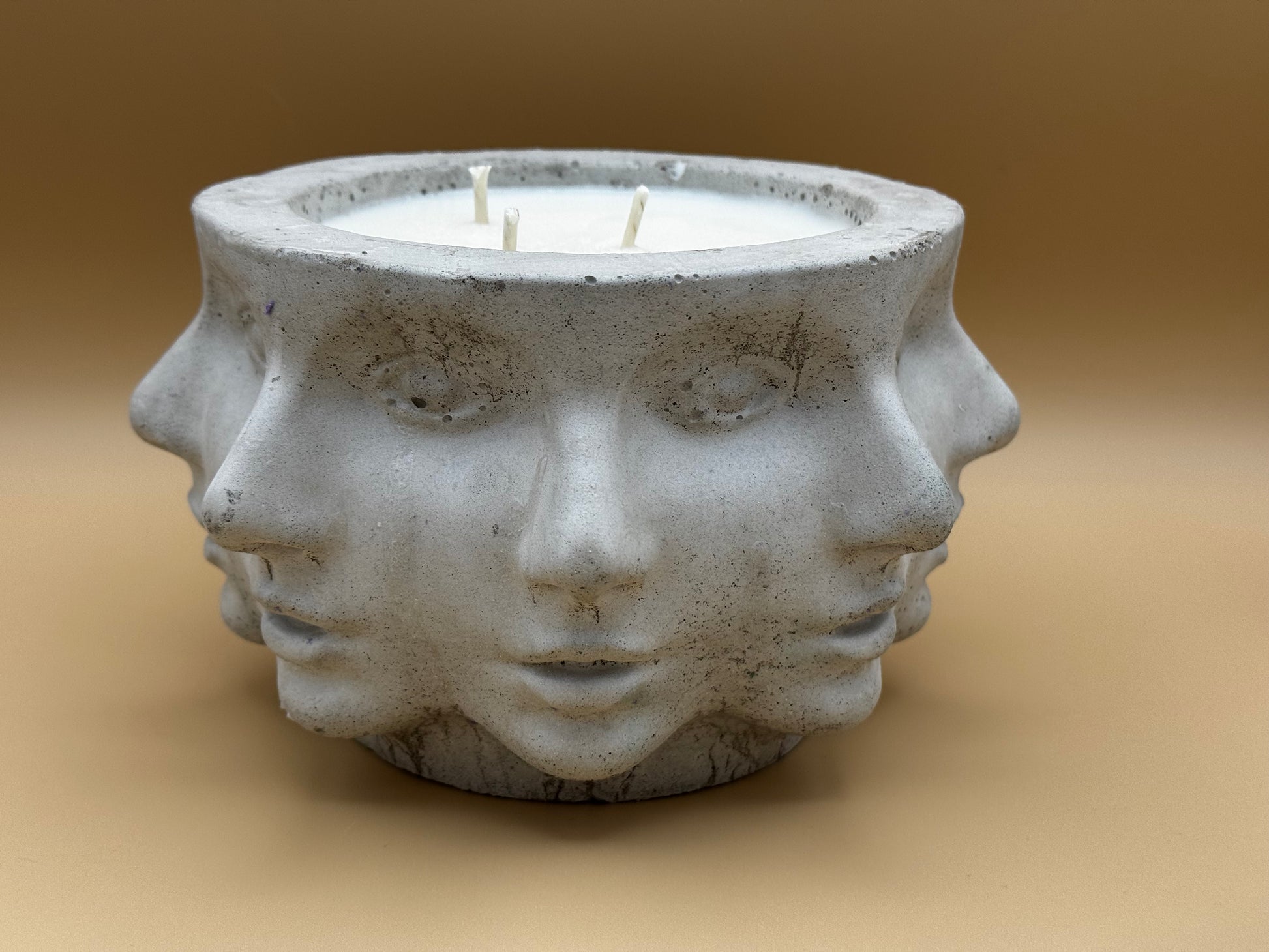 Concrete candle pot with multi-face design on a beige background