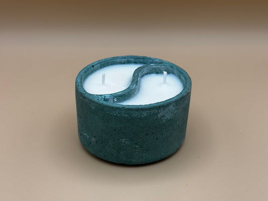 Cylindrical concrete candle holder with a Yin-Yang design on a beige background