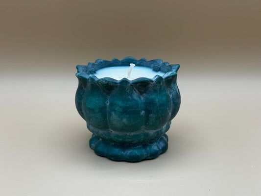 Green concrete candle holder with a white candle on a beige background