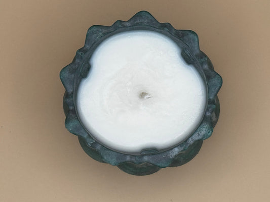 Top view White candle in a decorative green holder on a beige background