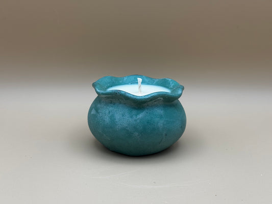 Teal Concrete container with a white candle inside on a beige background