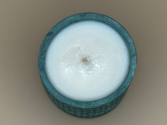 Top view  Teal textured candle holder with a white candle inside on a beige background