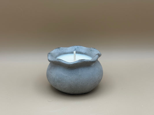 Concrete pot with a candle inside on a beige background