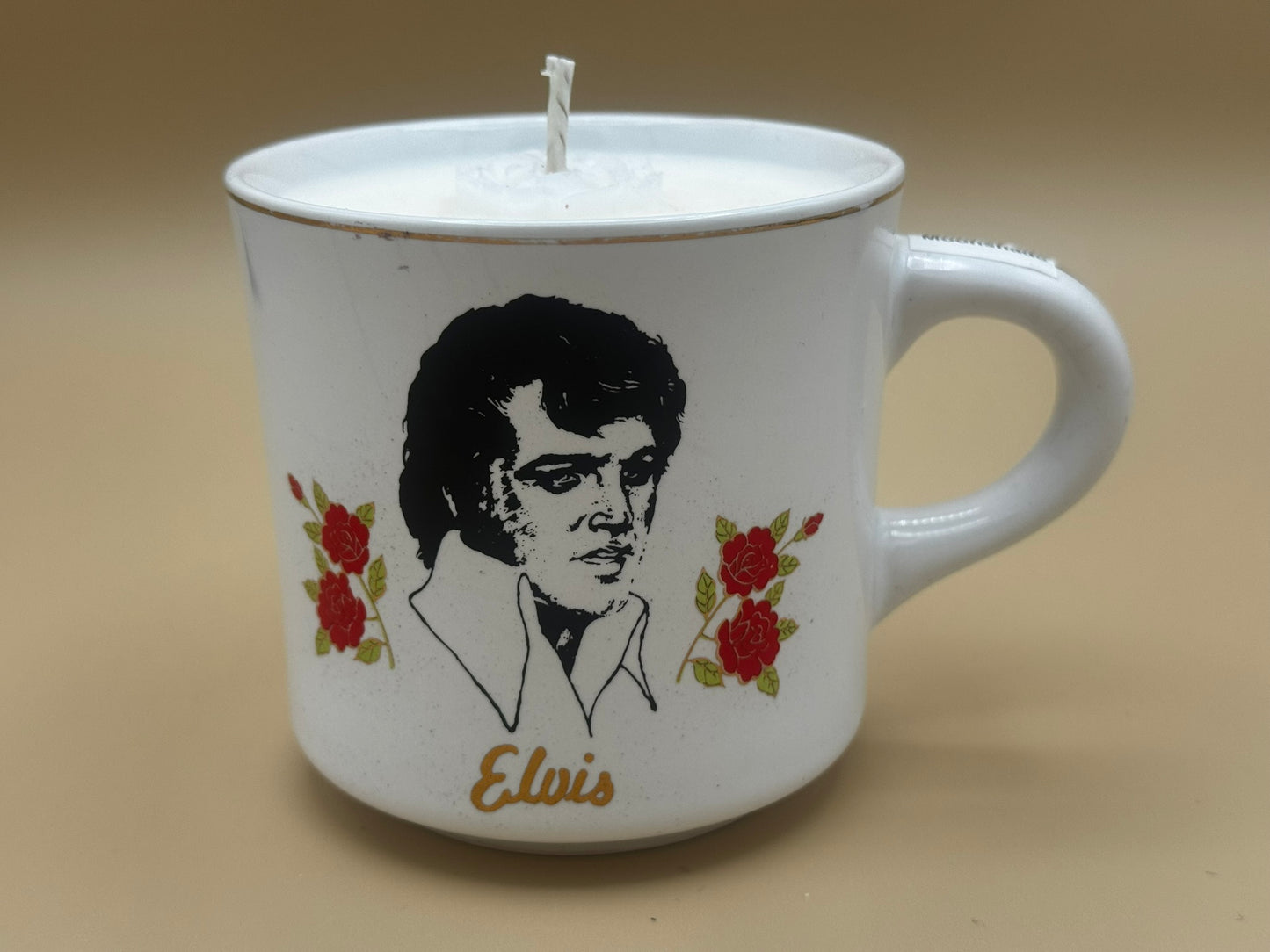 Candle in a mug with a portrait of Elvis Presley and flowers on a beige background
