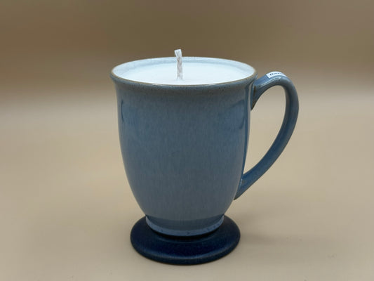 Blue mug with a candle inside on a beige background