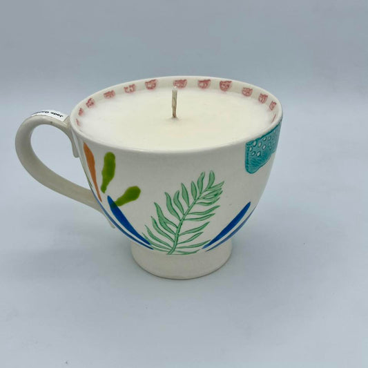 Ceramic mug with decorative elements used as a candle on a gray background