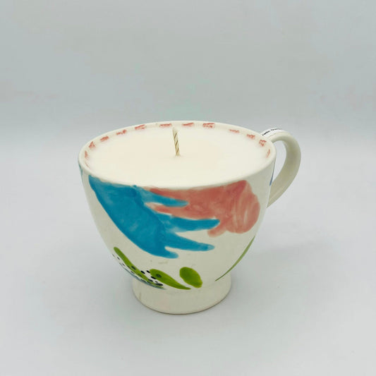 Ceramic mug with decorative elements used as a candle on a gray background