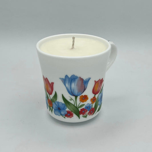 Candle in a mug with floral design on a gray background
